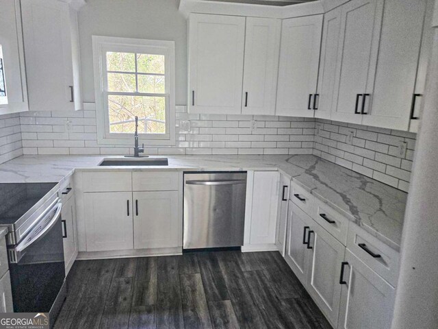 kitchen with a sink, dark wood-type flooring, appliances with stainless steel finishes, white cabinetry, and backsplash