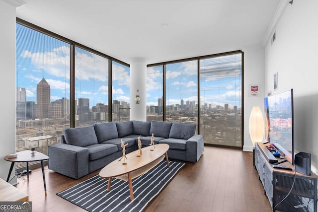 living area with expansive windows, visible vents, wood finished floors, and crown molding