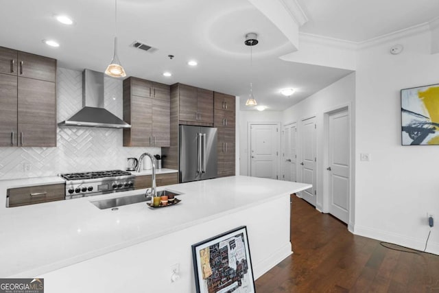 kitchen with a sink, decorative backsplash, light countertops, high end refrigerator, and wall chimney exhaust hood