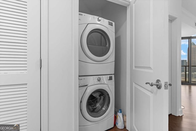 laundry area featuring laundry area, stacked washer / dryer, and wood finished floors