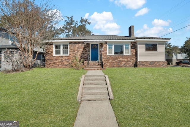 ranch-style house featuring brick siding, a chimney, a front lawn, and metal roof