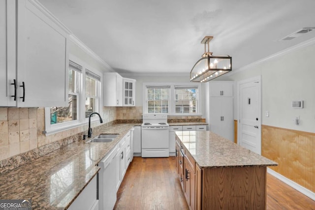 kitchen with glass insert cabinets, wainscoting, light wood-style floors, white appliances, and a sink