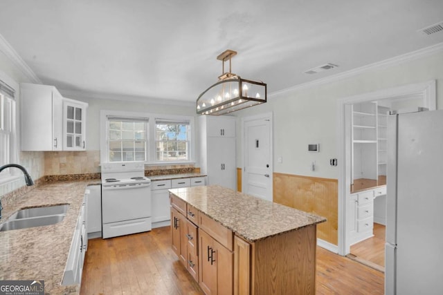 kitchen with light wood finished floors, visible vents, white appliances, and a sink