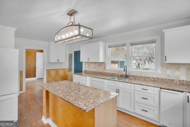 kitchen with light wood-style flooring, a sink, a kitchen island, white appliances, and white cabinets