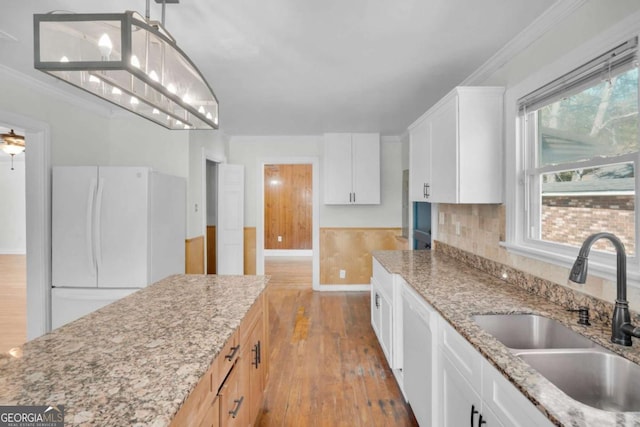 kitchen with white appliances, ornamental molding, wood-type flooring, and a sink