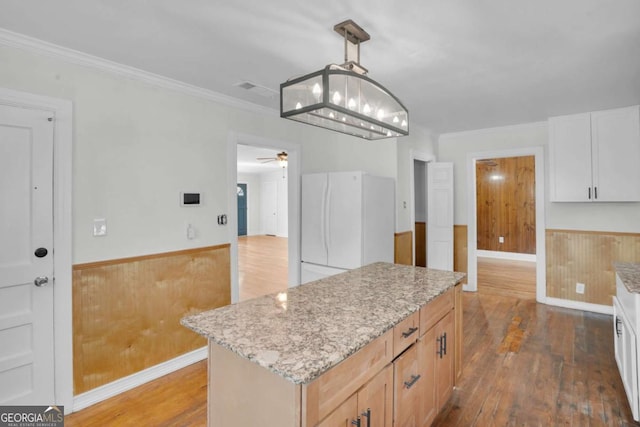 kitchen featuring crown molding, hardwood / wood-style floors, wainscoting, and freestanding refrigerator