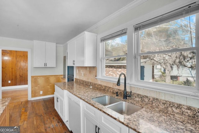 kitchen featuring ornamental molding, a sink, white cabinetry, white dishwasher, and light stone countertops