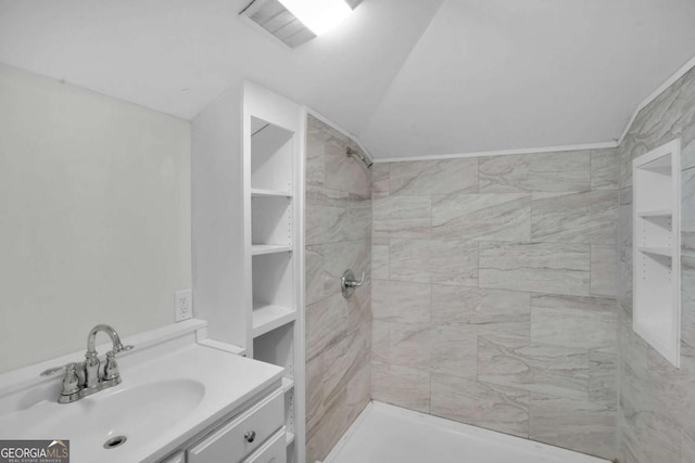 full bath with a tile shower, visible vents, vanity, and lofted ceiling