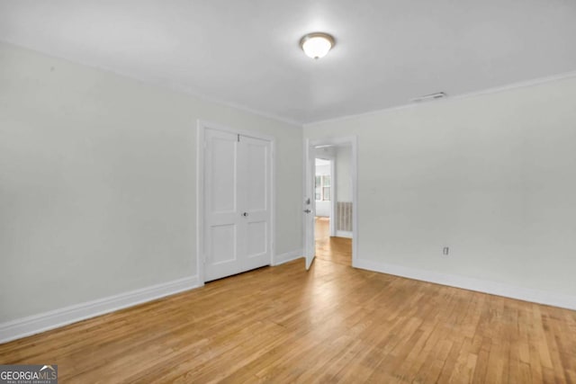 unfurnished bedroom featuring a closet, baseboards, visible vents, and wood finished floors