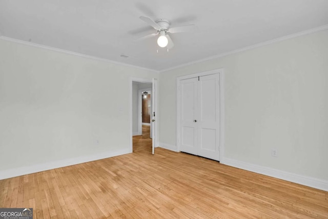 unfurnished bedroom featuring a closet, crown molding, light wood-type flooring, and baseboards