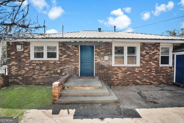 view of front of property featuring brick siding and metal roof