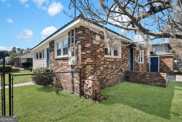 view of property exterior featuring a yard, fence, brick siding, and metal roof