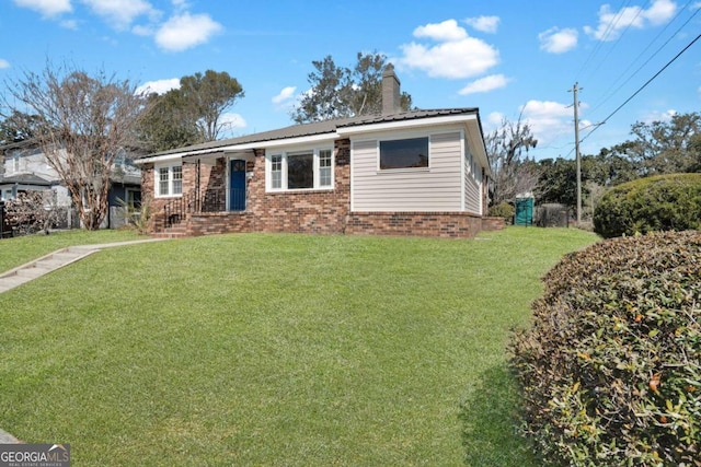 view of front of house with brick siding, a chimney, and a front lawn