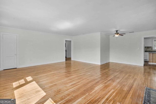 unfurnished living room featuring a ceiling fan, baseboards, and light wood finished floors