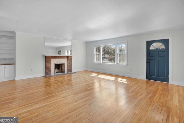 unfurnished living room featuring a fireplace, light wood-type flooring, and baseboards