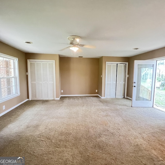 unfurnished bedroom featuring access to outside, multiple windows, and carpet