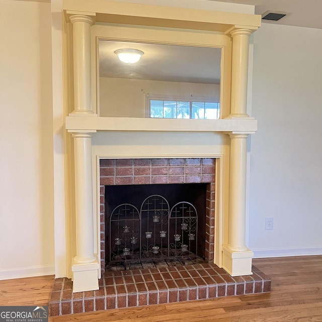 interior details featuring decorative columns, wood finished floors, baseboards, and a fireplace with raised hearth