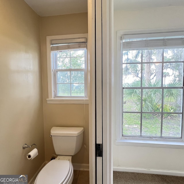 bathroom with plenty of natural light, toilet, and baseboards