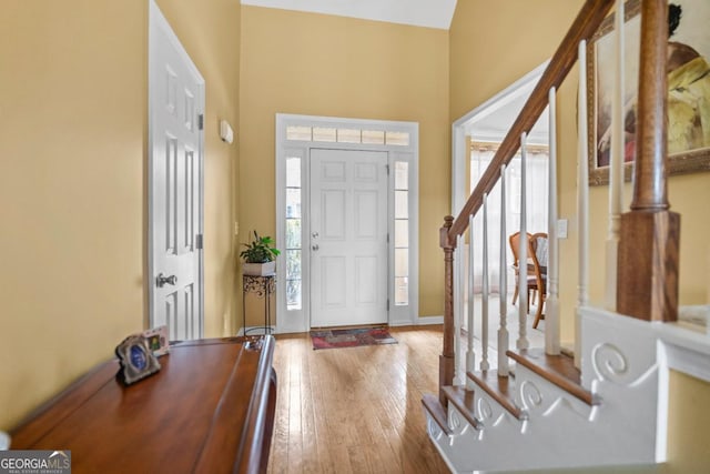 foyer with plenty of natural light, stairway, baseboards, and wood-type flooring