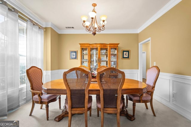 dining room featuring light carpet, visible vents, a notable chandelier, and a wainscoted wall