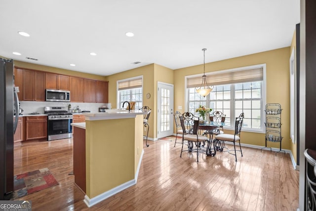 kitchen with stainless steel appliances, light wood finished floors, visible vents, and light countertops