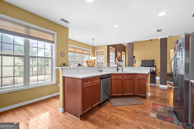 kitchen with visible vents, a sink, open floor plan, appliances with stainless steel finishes, and light countertops