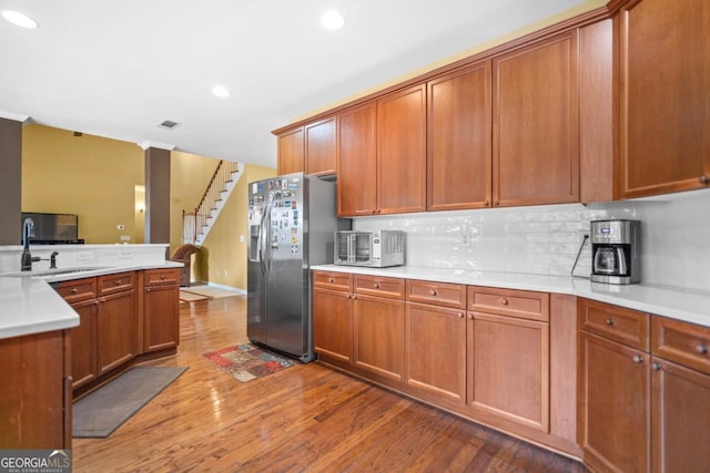 kitchen featuring brown cabinets, wood finished floors, light countertops, and stainless steel fridge with ice dispenser