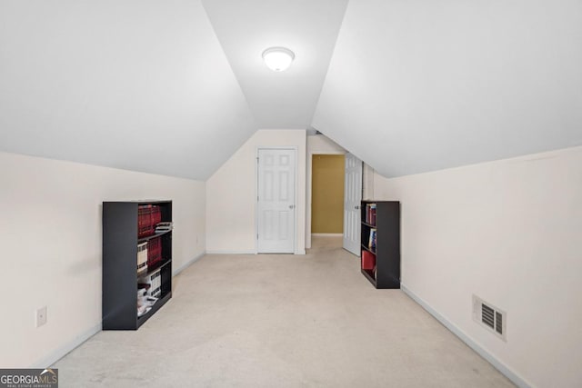 additional living space featuring lofted ceiling, light colored carpet, visible vents, and baseboards