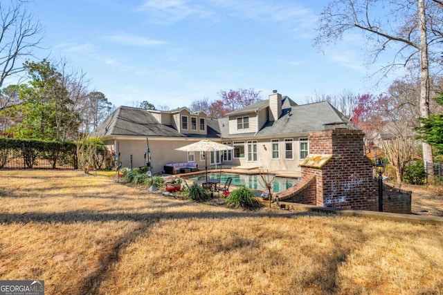 rear view of property with brick siding, a fenced in pool, fence, a yard, and a patio