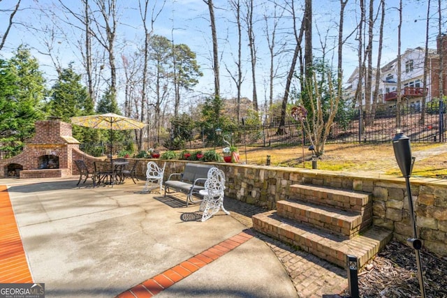 view of patio / terrace featuring outdoor dining space, fence, and an outdoor brick fireplace