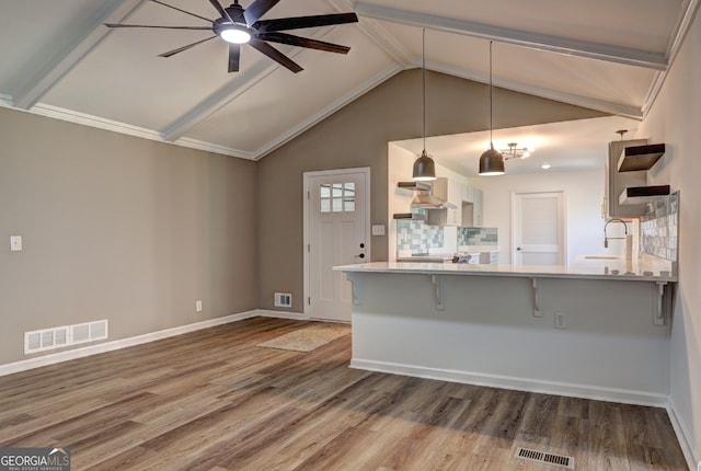 kitchen with visible vents, a sink, a kitchen bar, and wood finished floors