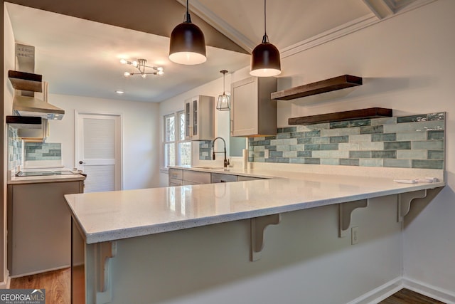 kitchen with tasteful backsplash, a peninsula, a breakfast bar area, and light stone countertops