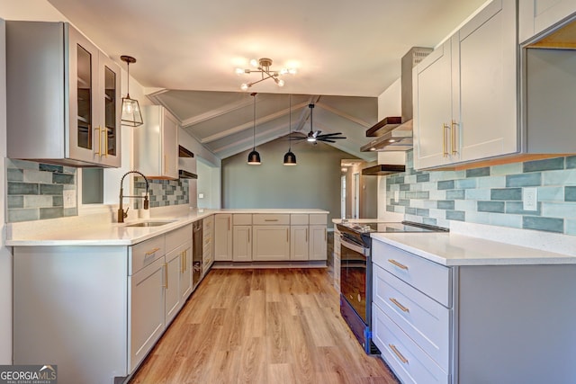 kitchen featuring light wood-style flooring, a peninsula, electric range, a ceiling fan, and a sink