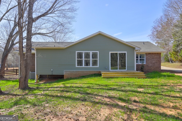 back of house with brick siding and a yard