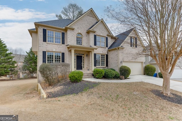 view of front of house featuring concrete driveway, a garage, brick siding, and roof with shingles