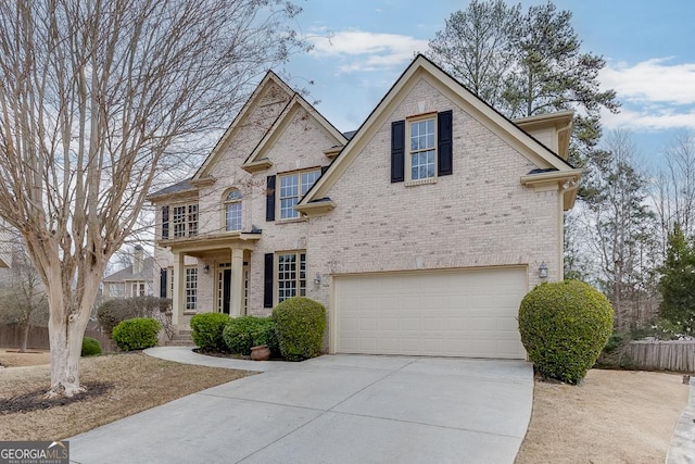 view of front of house with brick siding, an attached garage, driveway, and fence