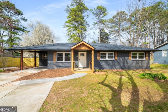 view of front of home with brick siding, an attached carport, a front lawn, fence, and driveway