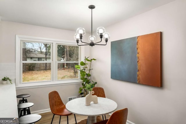 dining space featuring a notable chandelier, visible vents, baseboards, and wood finished floors