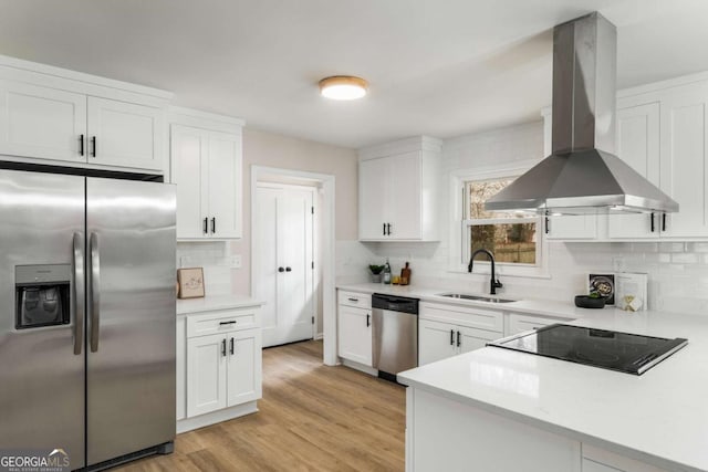 kitchen featuring light countertops, stainless steel appliances, island range hood, white cabinetry, and a sink