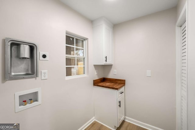 washroom with electric dryer hookup, washer hookup, wood finished floors, cabinet space, and baseboards