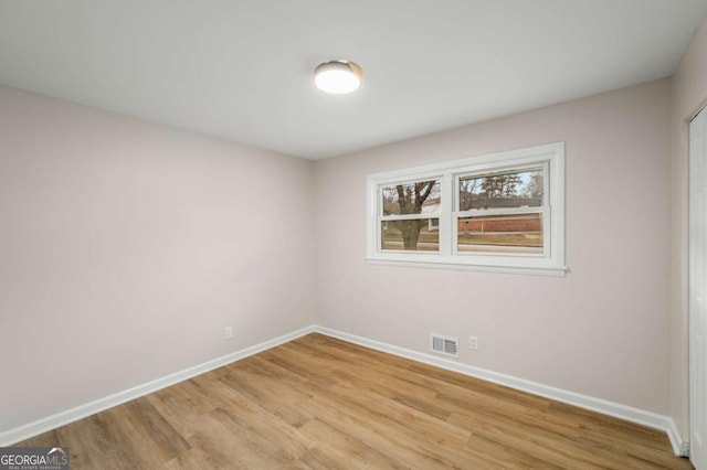 empty room featuring light wood-type flooring, visible vents, and baseboards