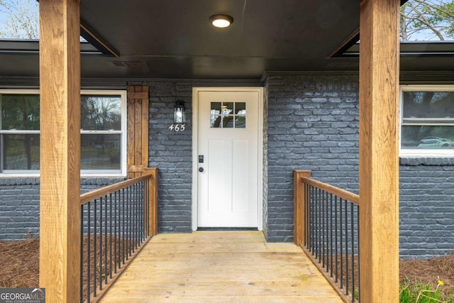 entrance to property featuring brick siding and covered porch