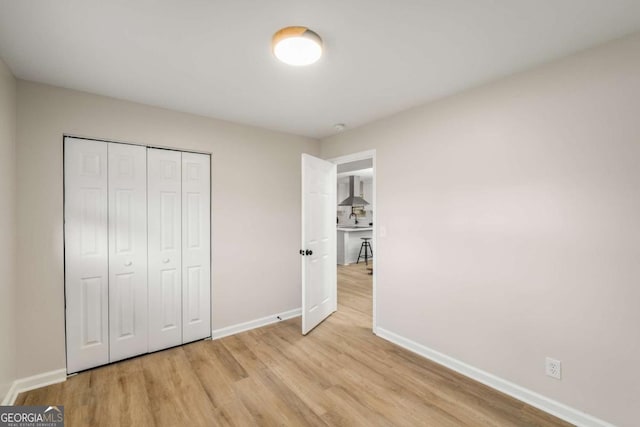 unfurnished bedroom featuring a closet, baseboards, and light wood-style floors