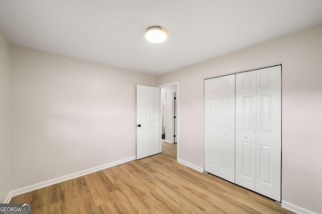 unfurnished bedroom featuring a closet, baseboards, and light wood finished floors