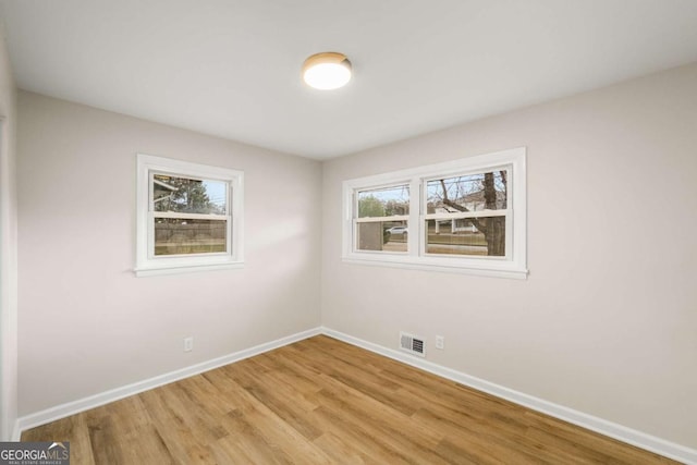 spare room featuring visible vents, light wood-style floors, and baseboards