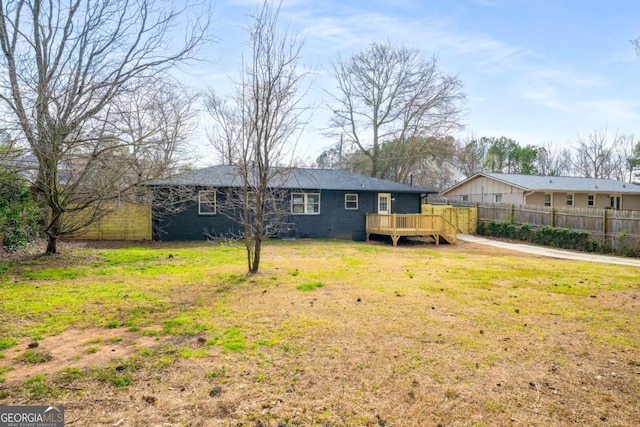 view of front of property featuring a front lawn, a deck, and fence