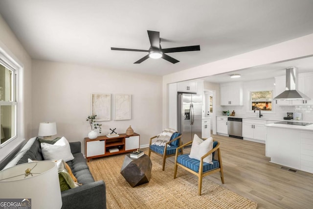 living area featuring light wood finished floors, visible vents, and ceiling fan