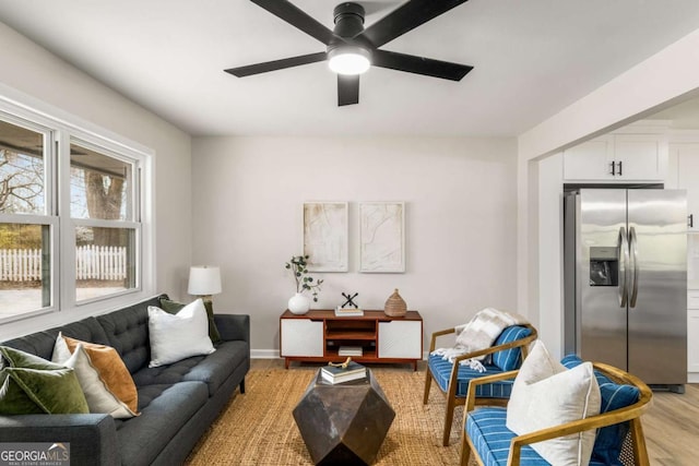 living room featuring light wood-style flooring, baseboards, and ceiling fan