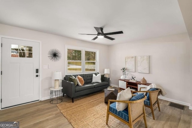 living area with visible vents, baseboards, a ceiling fan, and light wood finished floors