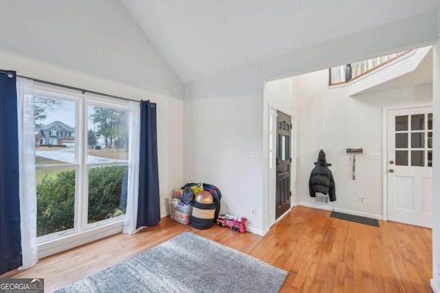 interior space with baseboards, wood finished floors, and vaulted ceiling